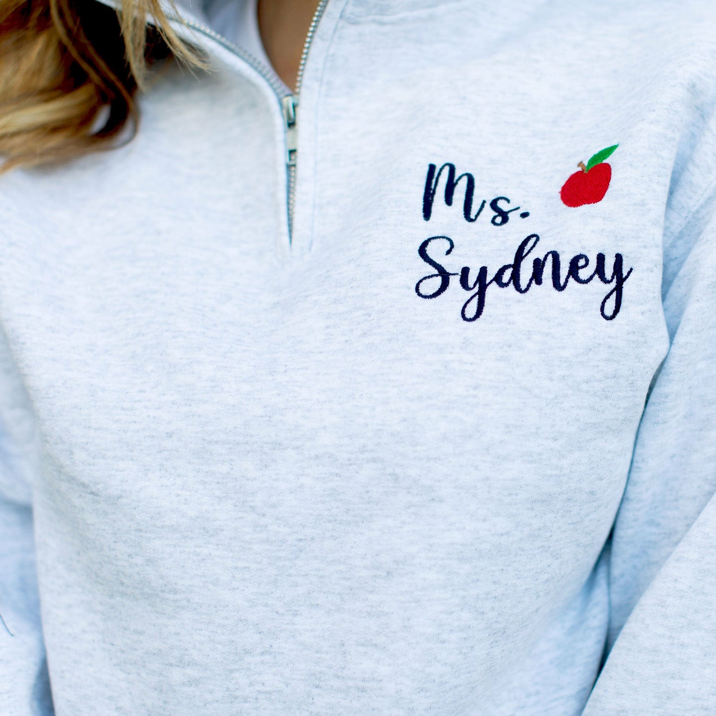 Light Gray pullover quarter zip with black name embroidery and red mini apple embroidery