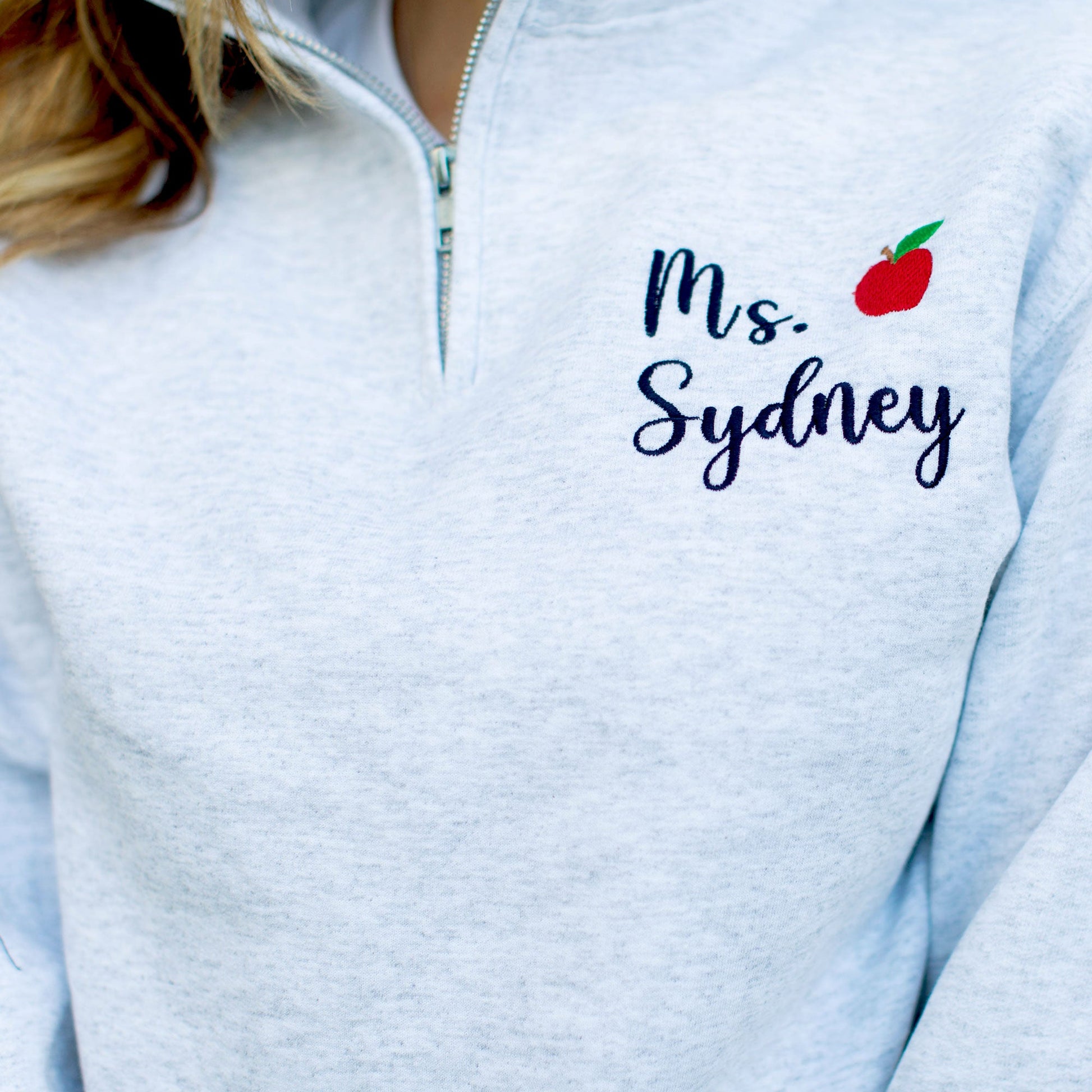 Light Gray pullover quarter zip with black name embroidery and red mini apple embroidery