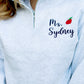 Light Gray pullover quarter zip with black name embroidery and red mini apple embroidery 