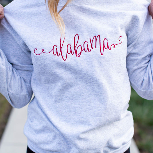 close up of custom state name embroidery across the chest of a gray pullover sweatshirt