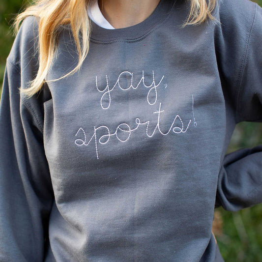 close up of yay, sports! embroidered across the chest of a gray sweatshirt