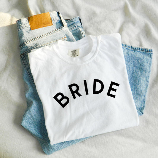 flatlay image of a white comfort colors t-shirt with a curved DTG desgin reading BRIDE in all caps