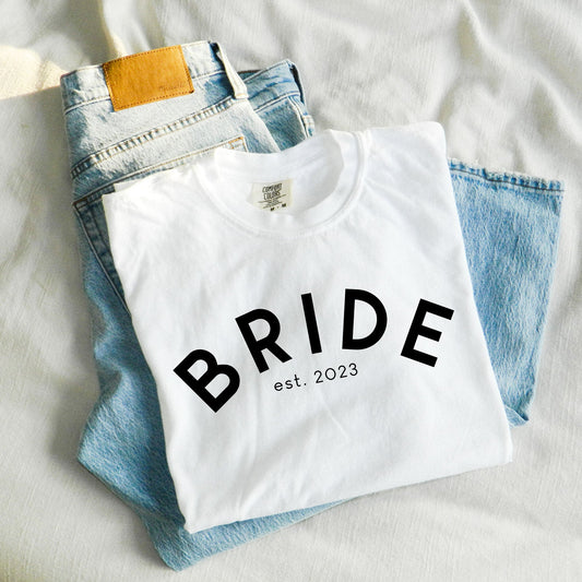white comfort colors t-shirt featuring a curved BRIDE print and custom wedding date