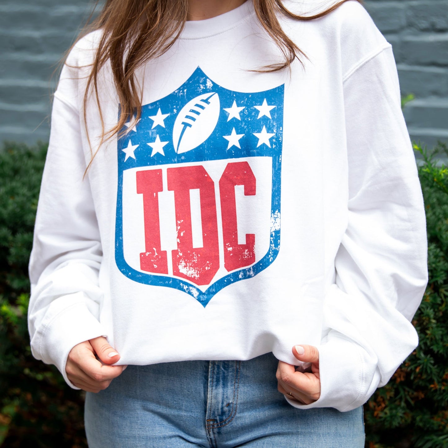 close up of woman wearing white crewneck with an idc football print