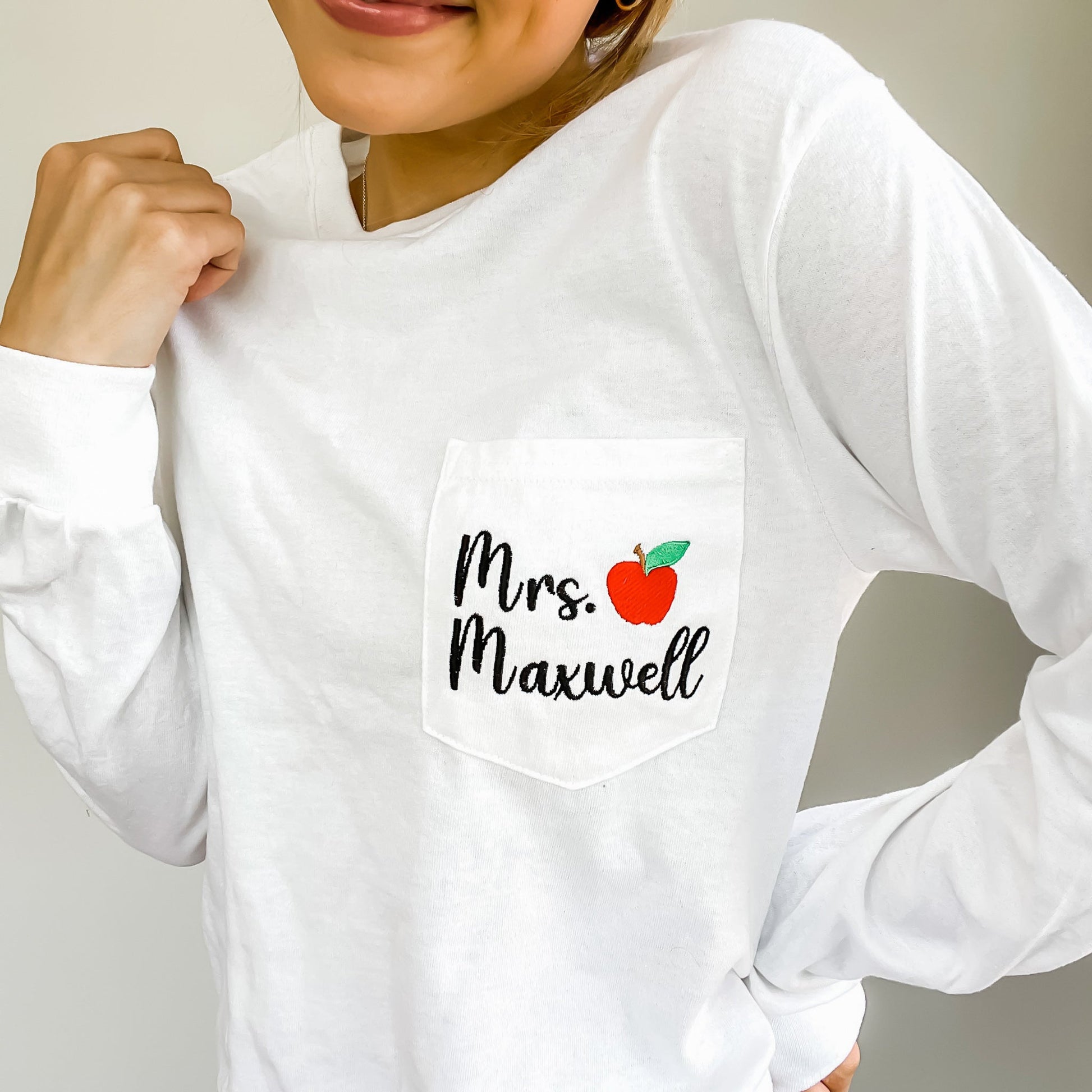 girl wearing long sleeved pocket t-shirt with teacher name and small red apple embroidered on the pocket