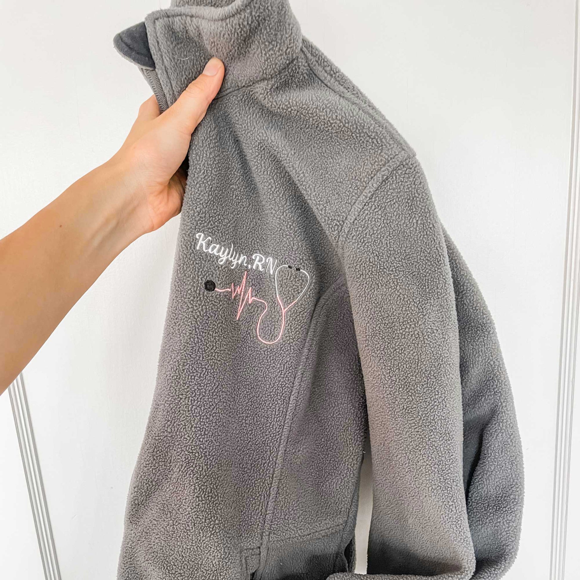 gray midweight fleece full zip jacket with a personalized name, credentials, and stethoscope embroidery design