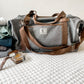 photo of gray duffel with clothing, watch and cologne beside it 