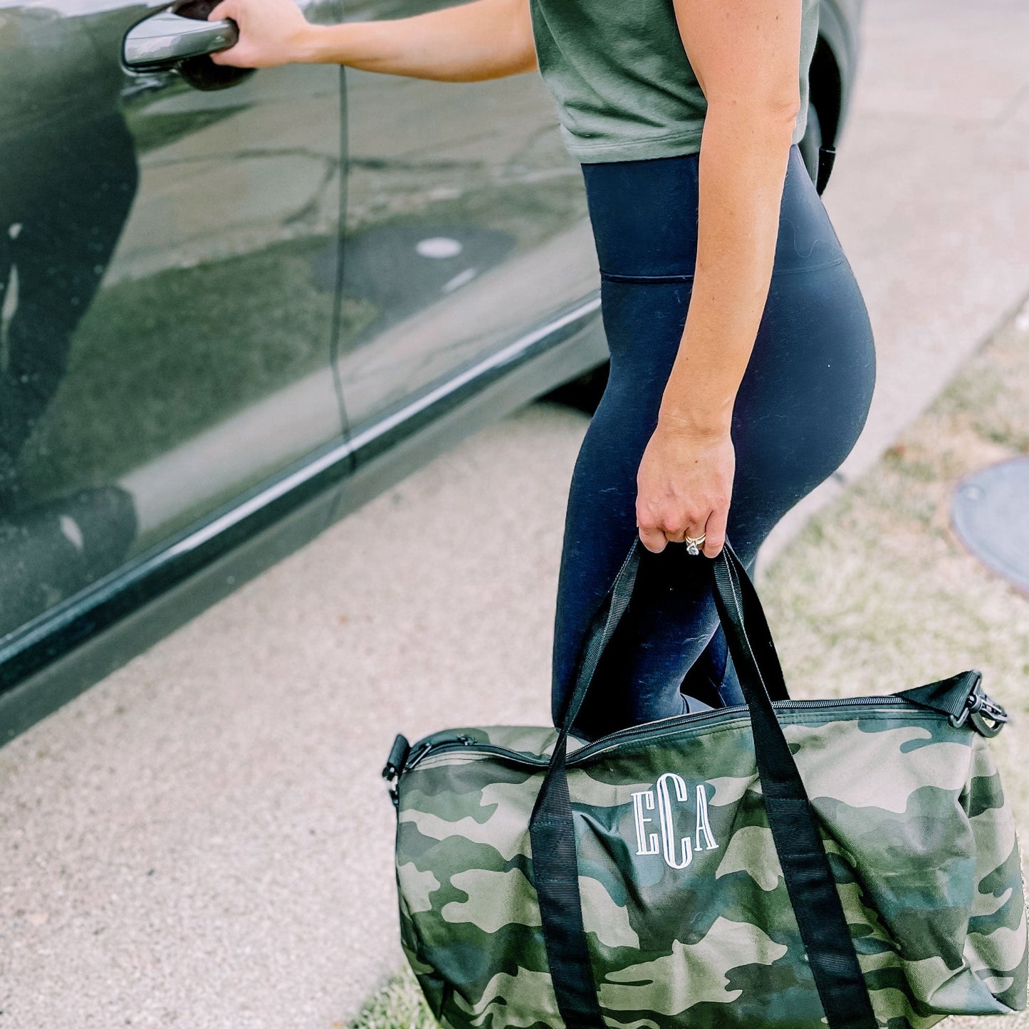 woman about to open car door holding camo duffle