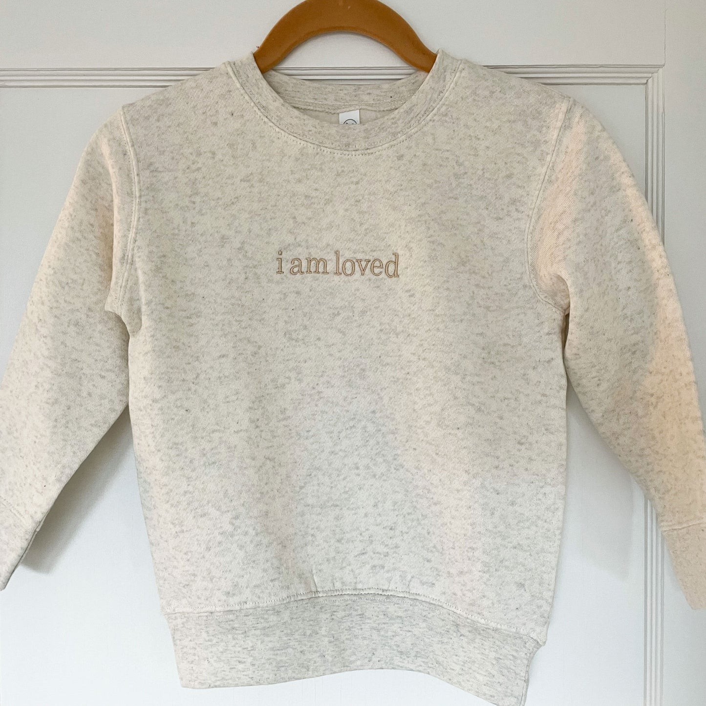 crewneck sweatshirt with i am loved embroidered in lowercase across the chest