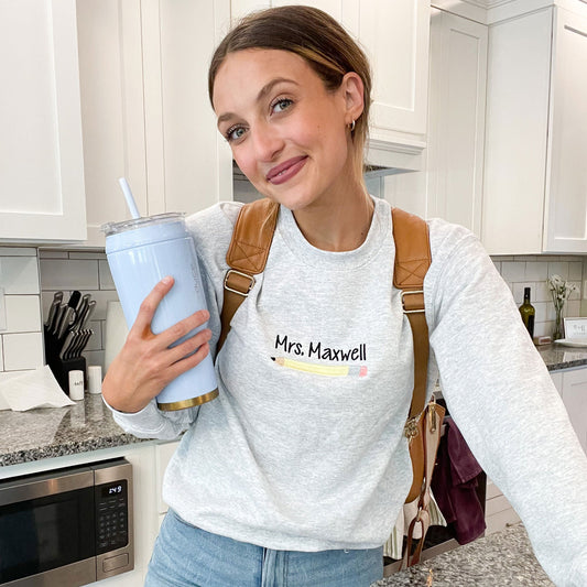 woman wearing a light gray sweatshirt with personalized name and number two pencil embroidery