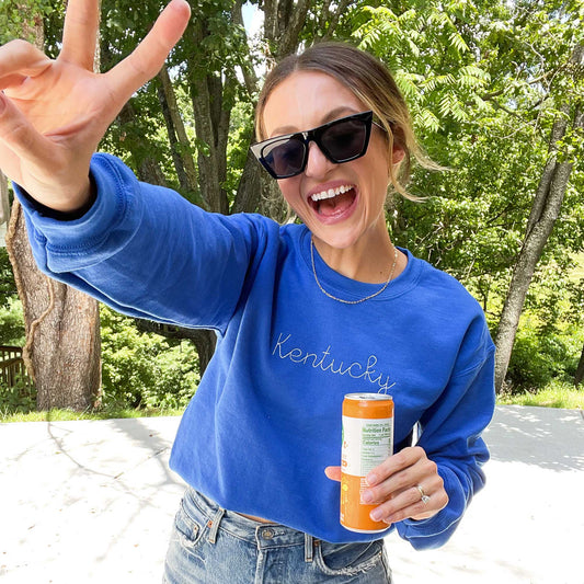 woman wearing a royal blue sweatshirt with kentucky embroidered across the chest in a white thread