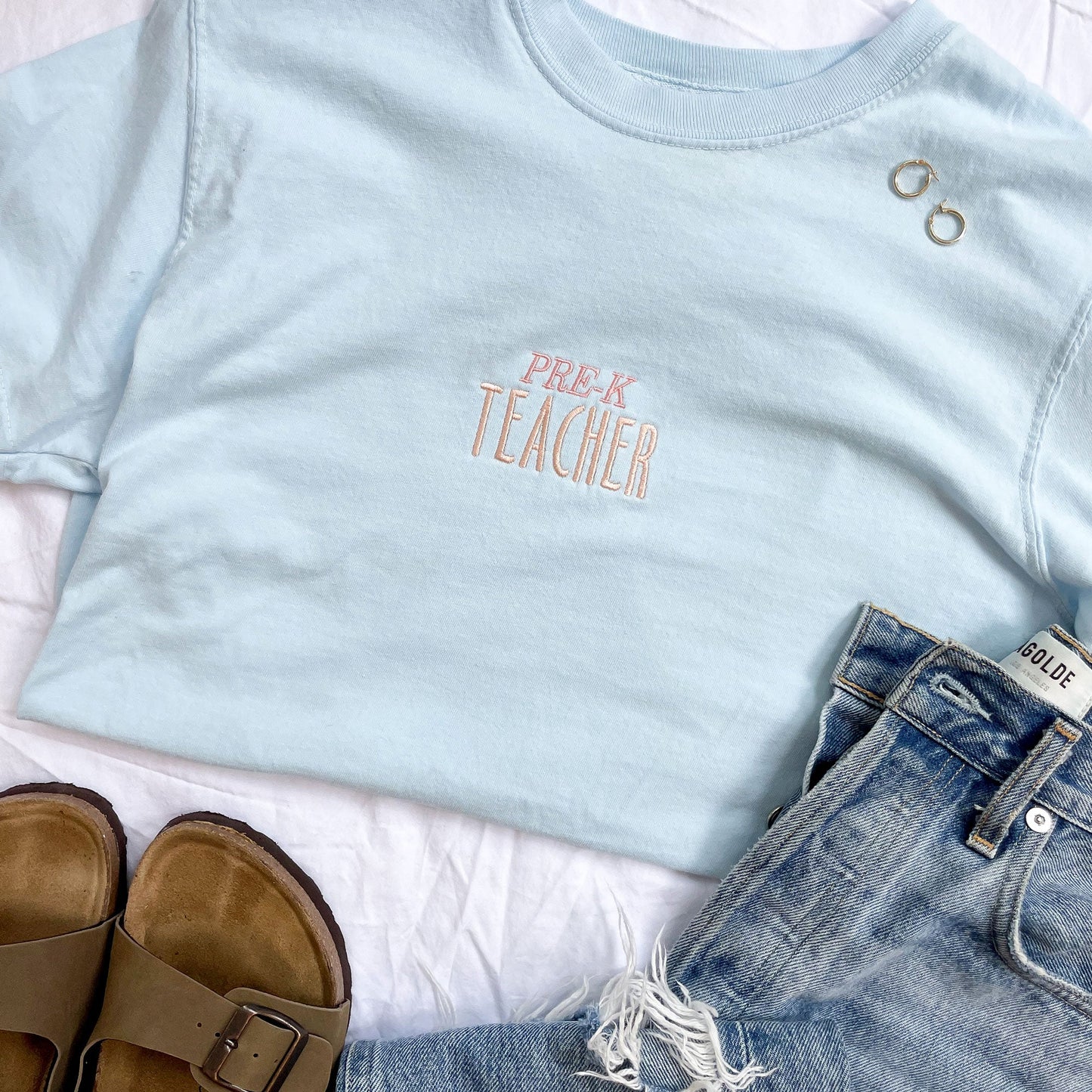 flat lay of light blue shirt with centered embroidery with Pre-K teacher