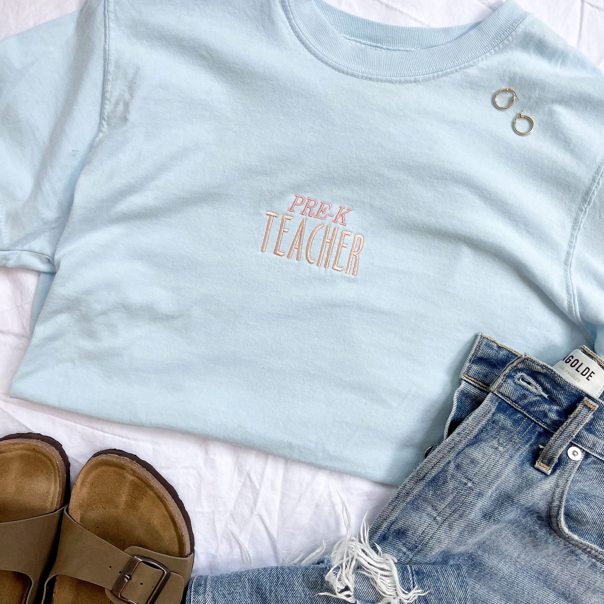 flat lay of light blue shirt with centered embroidery with Pre-K teacher