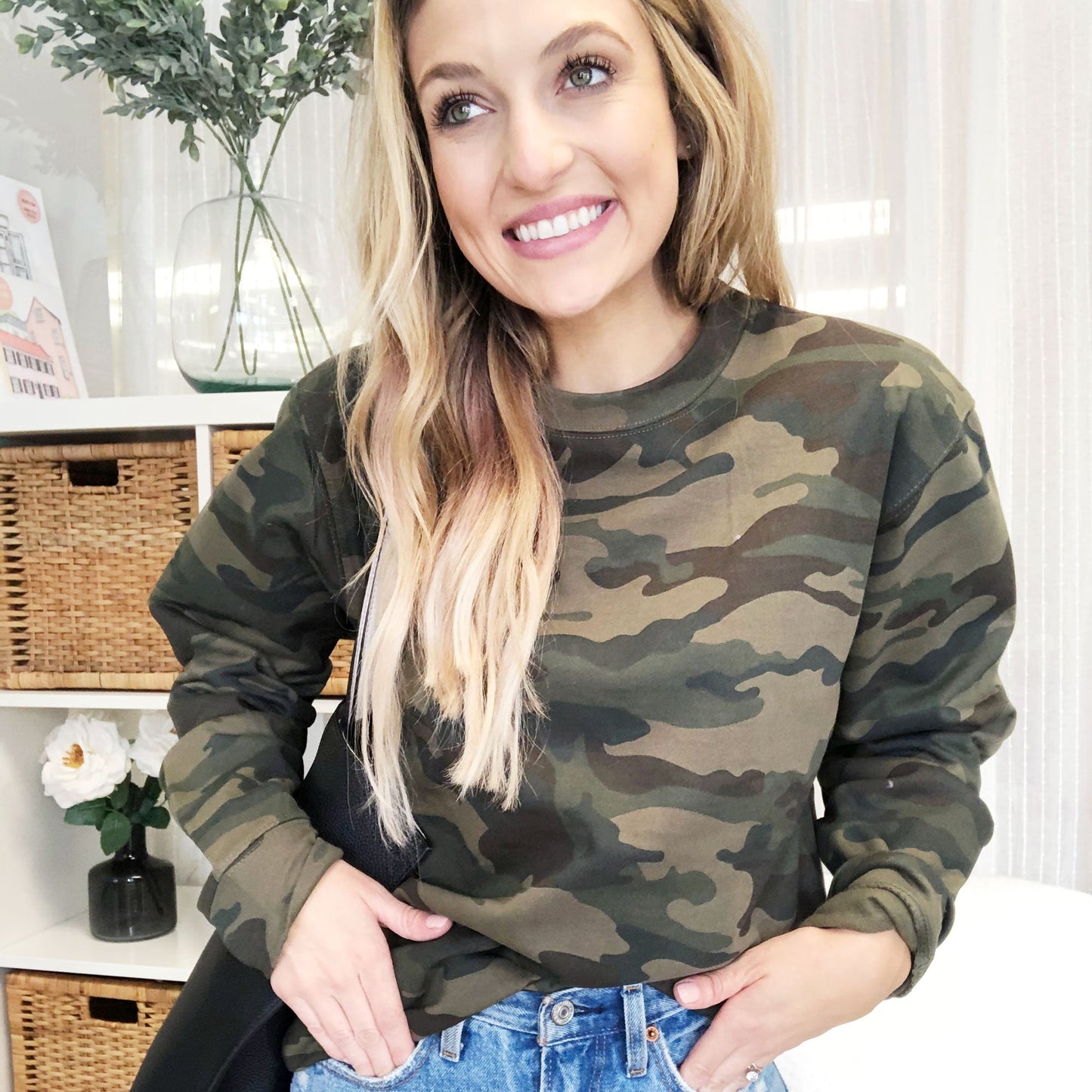 young woman wearing a crewneck sweatshirt with a traditional army green camo print