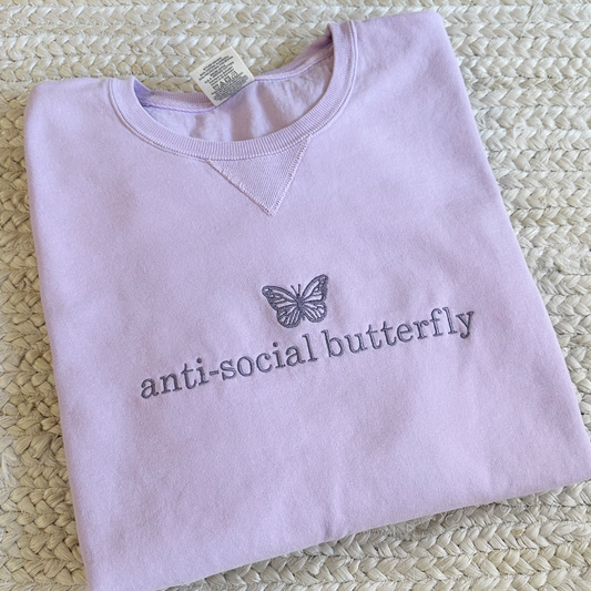 purple sweatshirt with anti-social butterfly embroidered across the chest