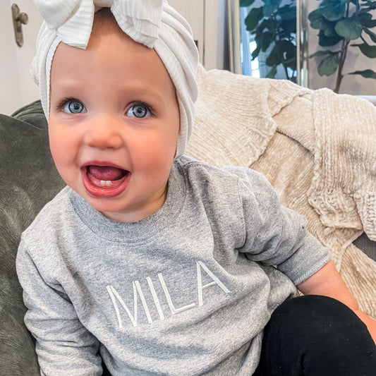 little girl with big eyes wearing heather gray crewneck 