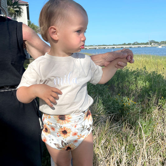 toddler girl at beach wearing heather dust embroidered shirt