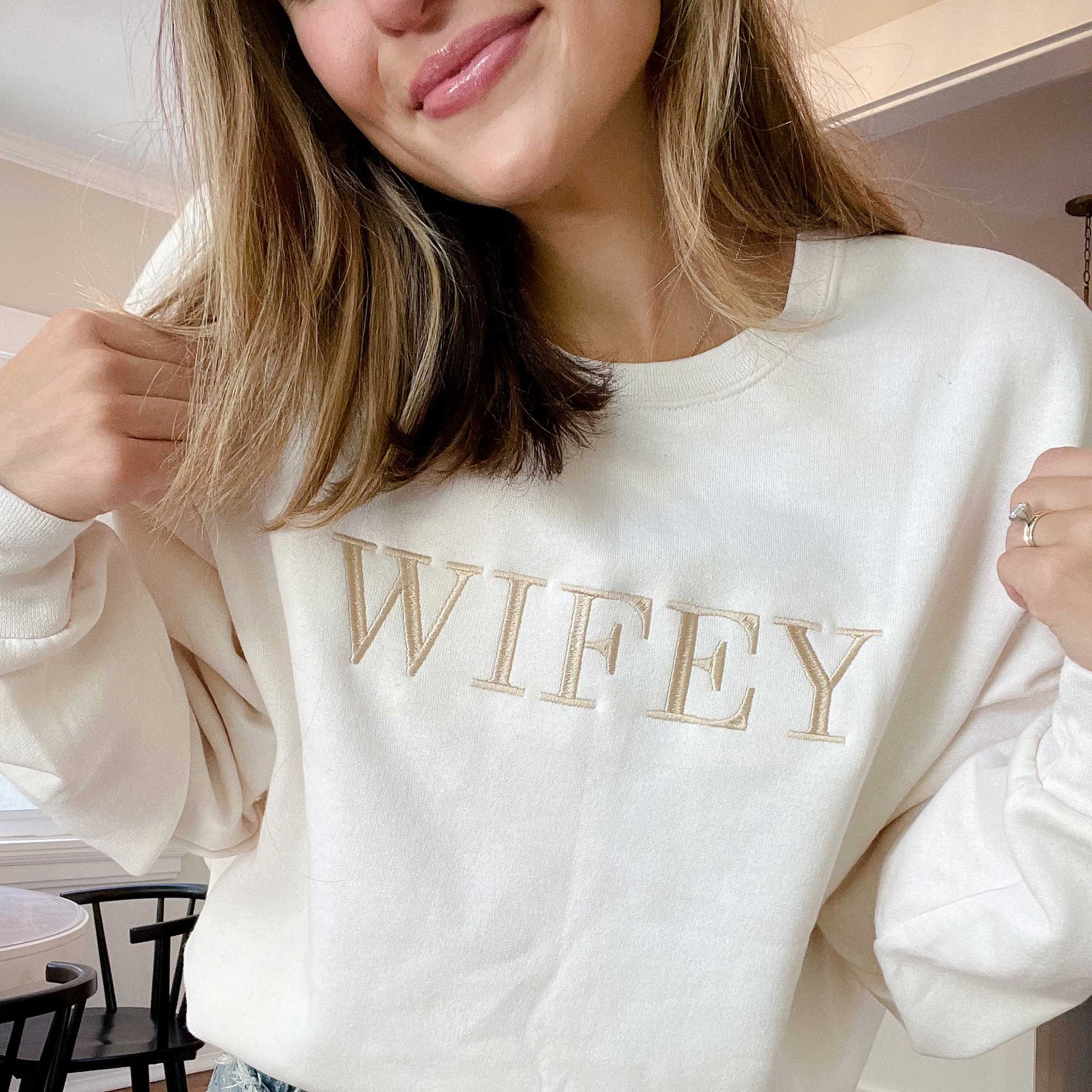 close up of a woman wearing an embroidered wifey crewneck