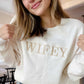 close up of a woman wearing an embroidered wifey crewneck