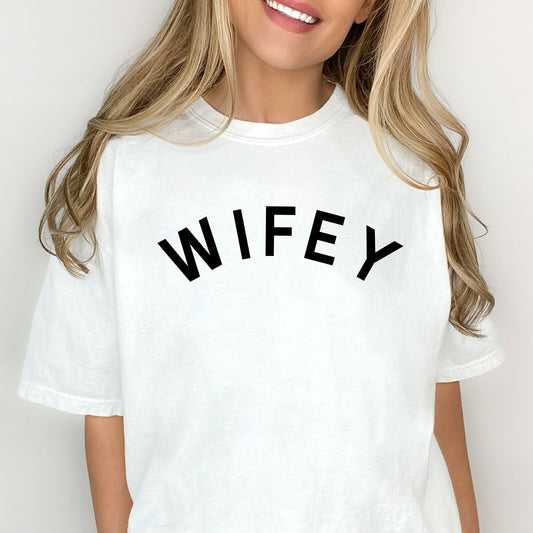 woman wearing an oversized white comfort colors t-shirt with an arched wifey print across the chest in black ink