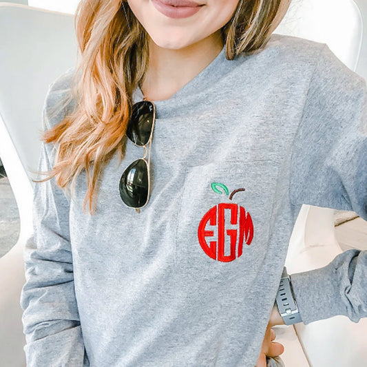 Woman wearing long sleeved athletic heather gray shirt with an apple monogram embroidered on the pocket 