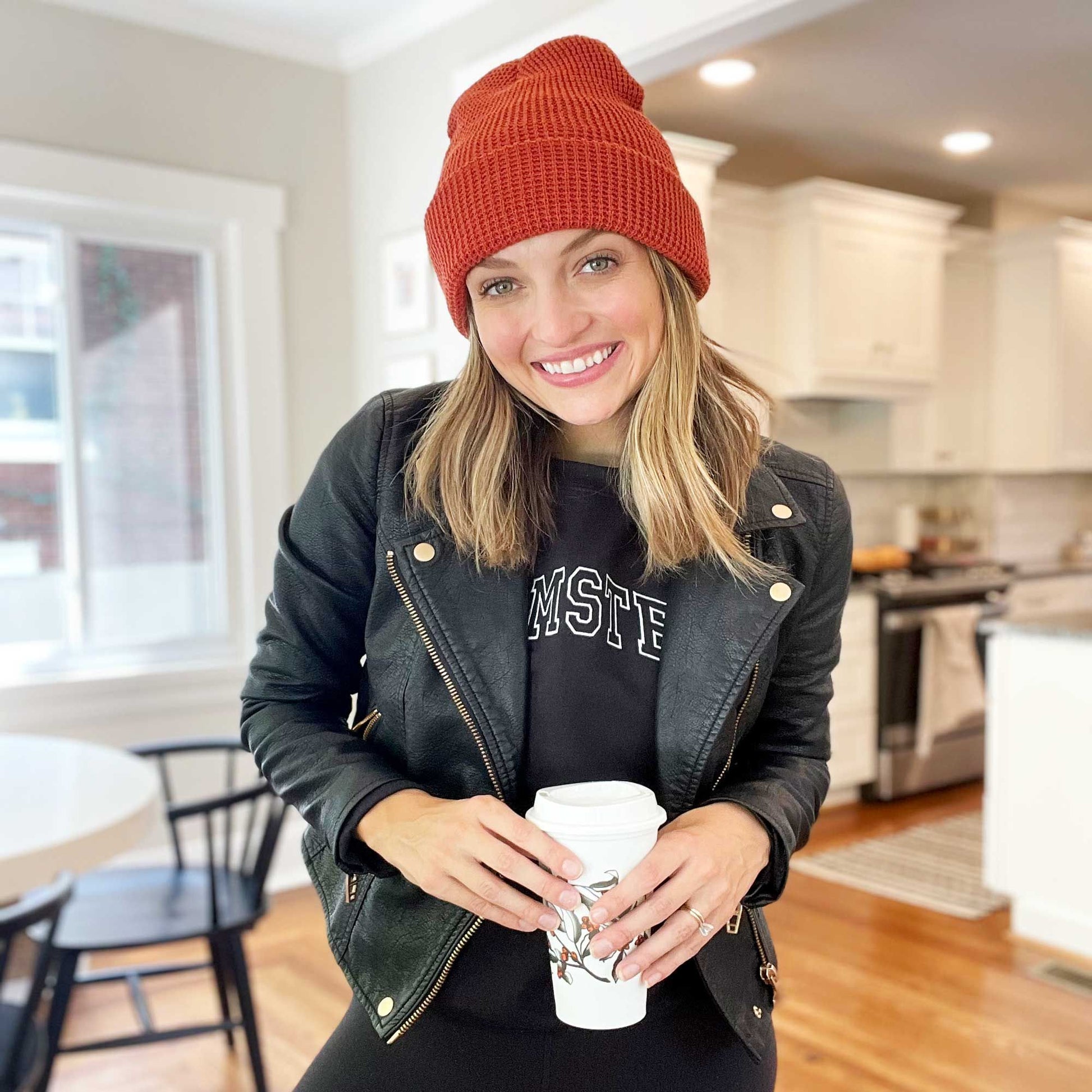 woman wearing a black leather jacket and a rust colored waffle knit beanie