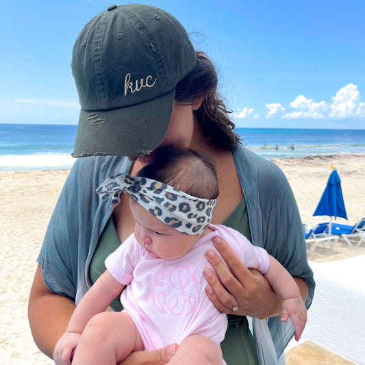 baby girl wearing a pink short sleeve infant bodysuit featuring a custom monogram held by aunt