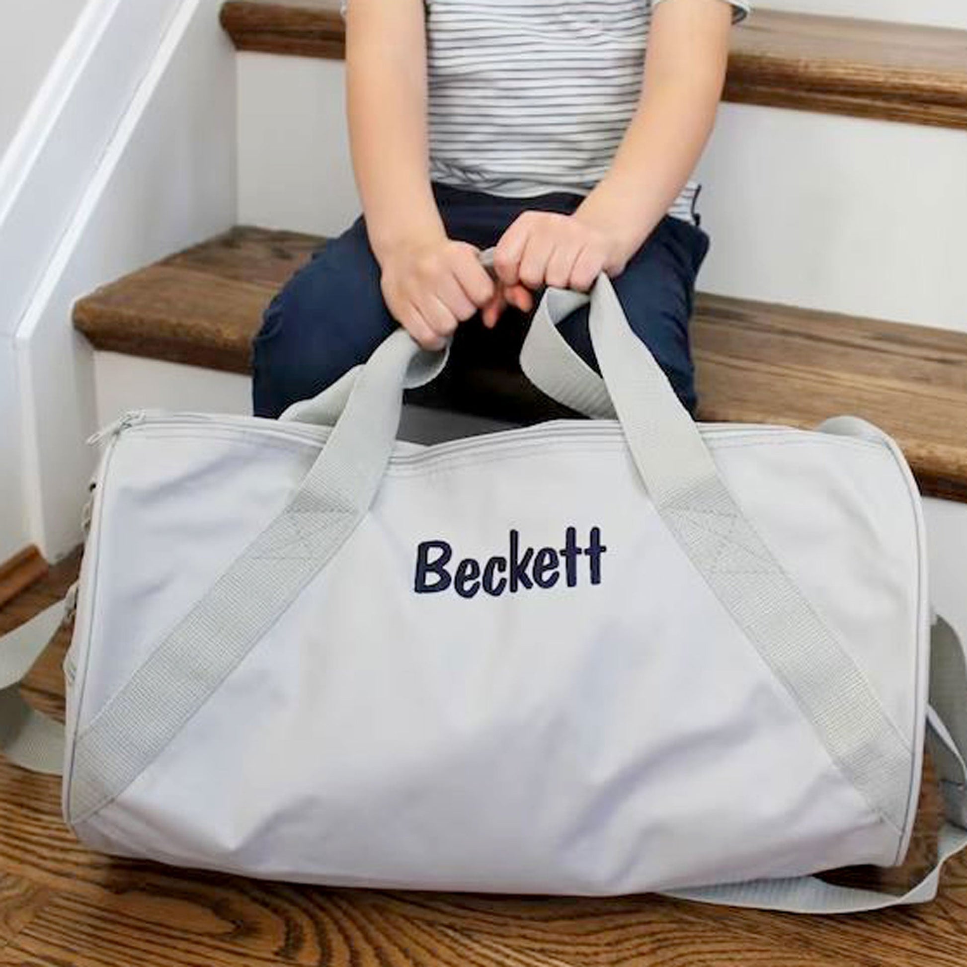 child holding youth duffle while sitting on steps
