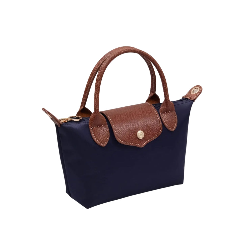 A navy blue canvas handbag with brown leather handles, trim, and a front flap secured by a gold-tone snap button, shown on a plain white background.