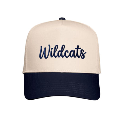 A structured baseball cap with a cream-colored front panel and brim, featuring the word 'Wildcats' embroidered in navy blue script across the front, with a dark navy blue curved brim and matching button on top.