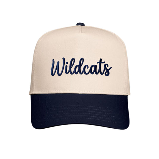 A structured baseball cap with a cream-colored front panel and brim, featuring the word 'Wildcats' embroidered in navy blue script across the front, with a dark navy blue curved brim and matching button on top.