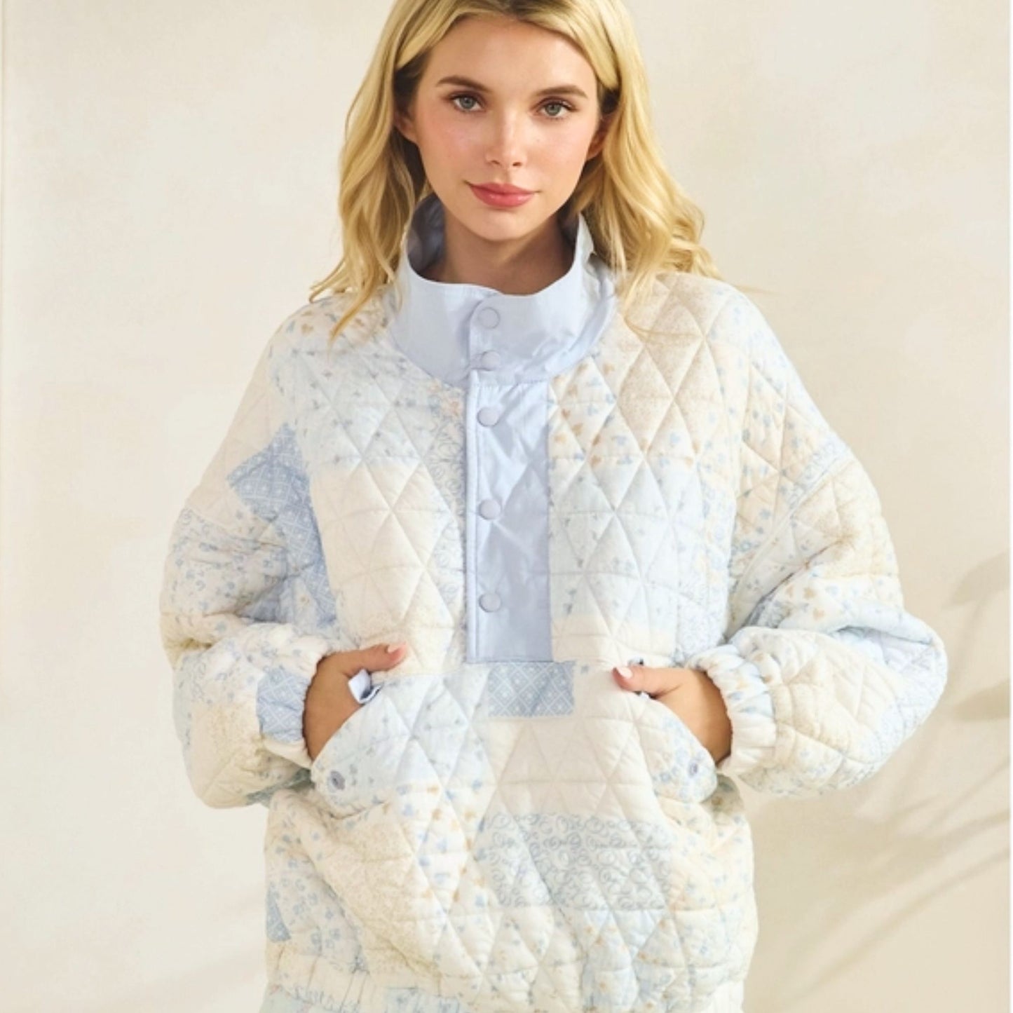 Woman wearing a quilted white and blue pullover on a beige background