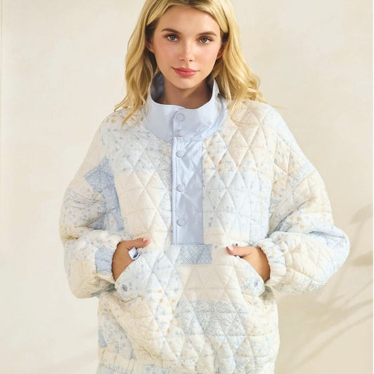 Woman wearing a quilted white and blue pullover on a beige background