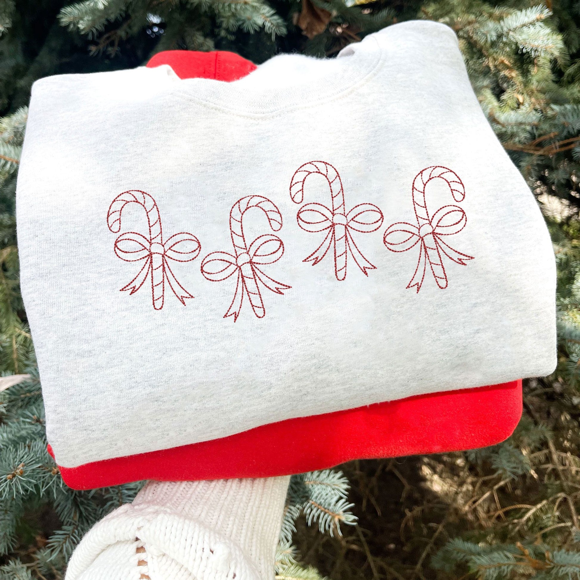 Ash sweatshirt with 4 staggered outlined candy canes with bows across the chest in red thread.