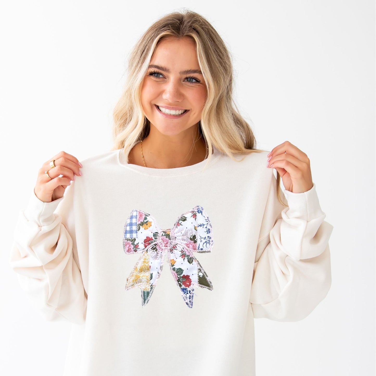 woman wearing a sweet cream crewneck sweatshirt with a custom embroidered bow with vintage inspired patchwork quilted colorful printed fabric