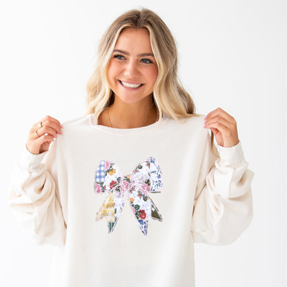 woman wearing a sweet cream crewneck sweatshirt with a custom embroidered bow with vintage inspired patchwork quilted colorful printed fabric