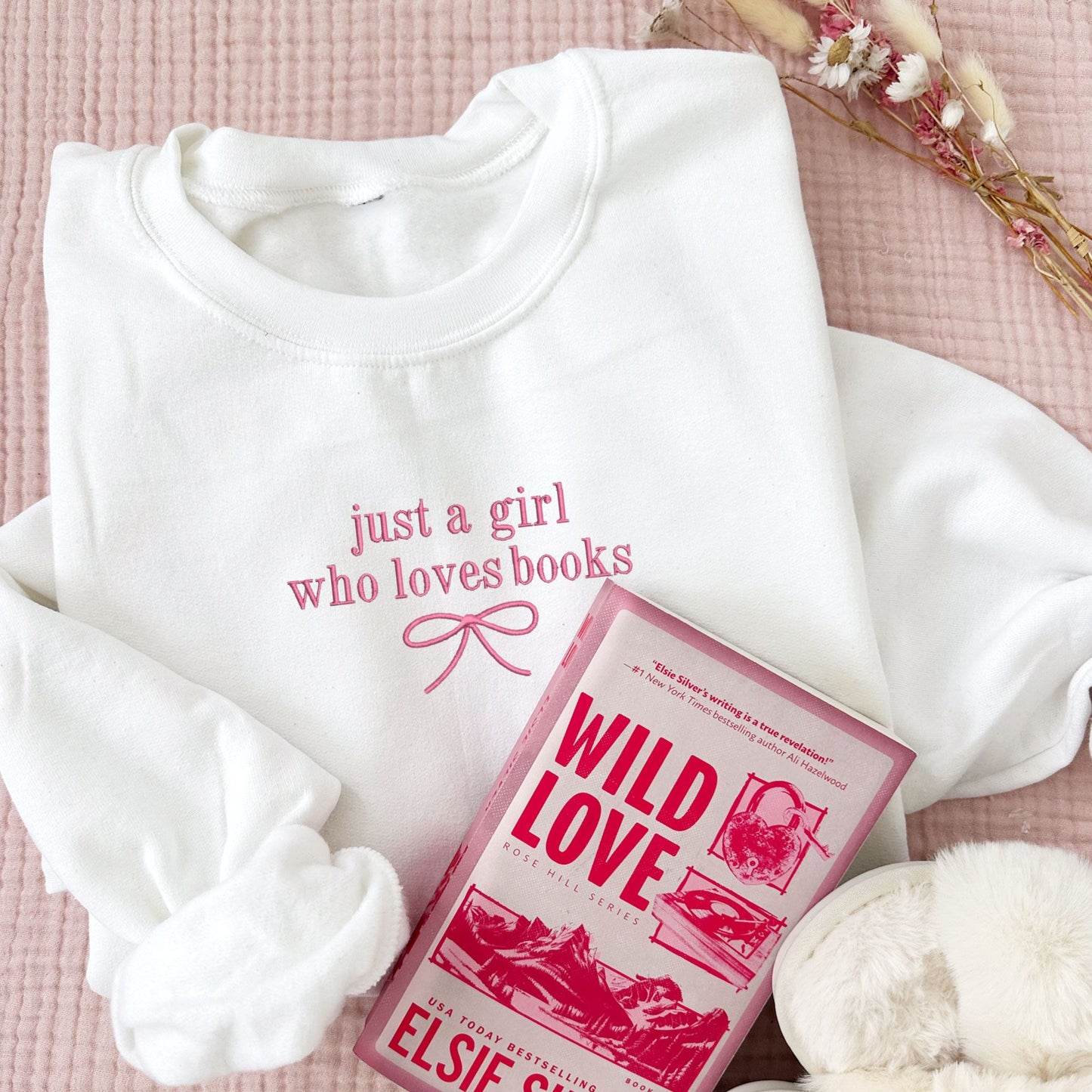 white crewneck sweatshirt with just a girl who loves books and a dainty bow embroidered on the center chest