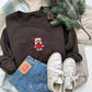 Brown sweatshirt with a teddy bear design, Levi's jeans, white sneakers, and Christmas decorations on a soft surface.