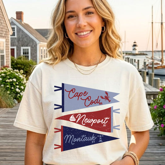 Woman wearing a t-shirt with 'Cape Cod', 'Newport', and 'Montauk' designs outdoors.