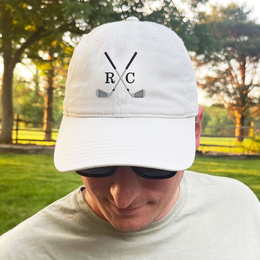 man standing in his backyard wearing a stone baseball hat with custom crossed golf club and 2 initial monogram embroidered design