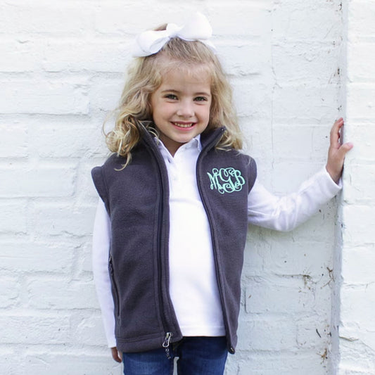 young girl wearing a navy vest with embroidered monogram on the left chest