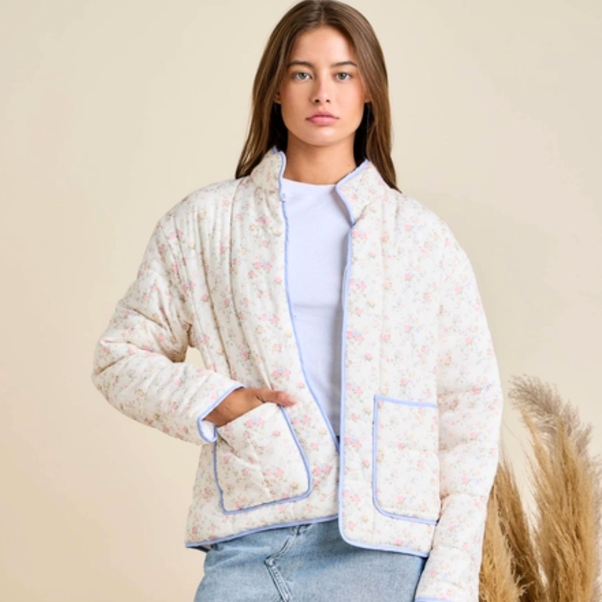 Woman wearing a floral quilted jacket against a beige background