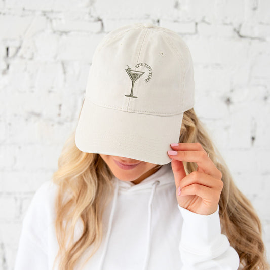 woman wearing a stone khaki baseball hat with custom embroidered martini glass tini time design in an olive thread