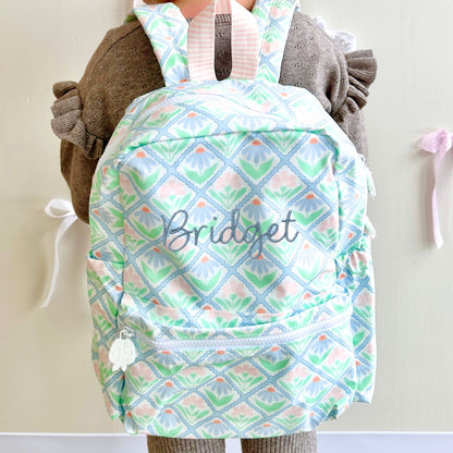 Backpack with pastel floral pattern and 'Bridget' embroidery, worn by a person.