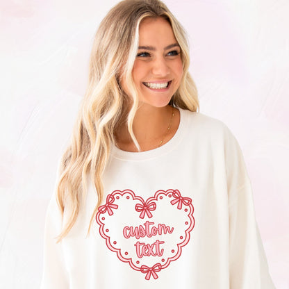 Woman wearing a sweet cream sweatshirt with printed a red heart doily design and 'custom text' on the front center chest 