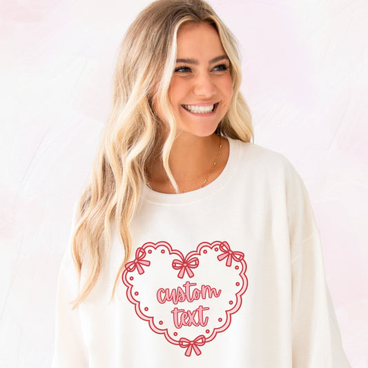 Woman wearing a sweet cream sweatshirt with printed a red heart doily design and 'custom text' on the front center chest 