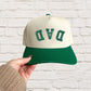 green two-tone canvas trucker hat with custom upside down curved athletic font DAD embroidered design in green thread.