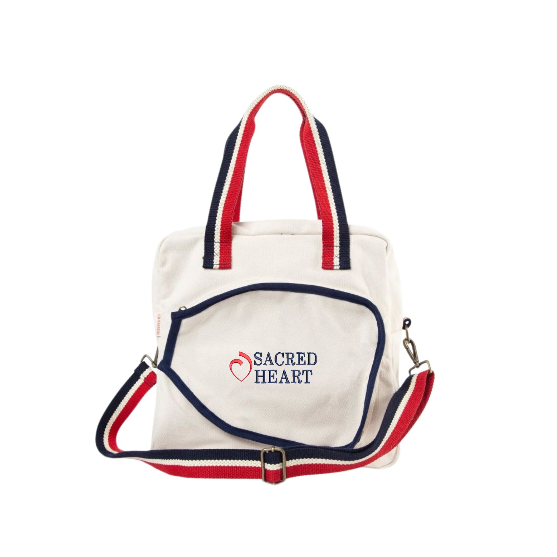natural canvas pickleball bag with red and navy striped handle and crossbody strap, featuring a sacred heart logo and text embroidered on the front center paddle pocket