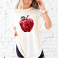 young woman wearing an ivory comfort colors t-shirt with large glitter apple print across the front of the chest