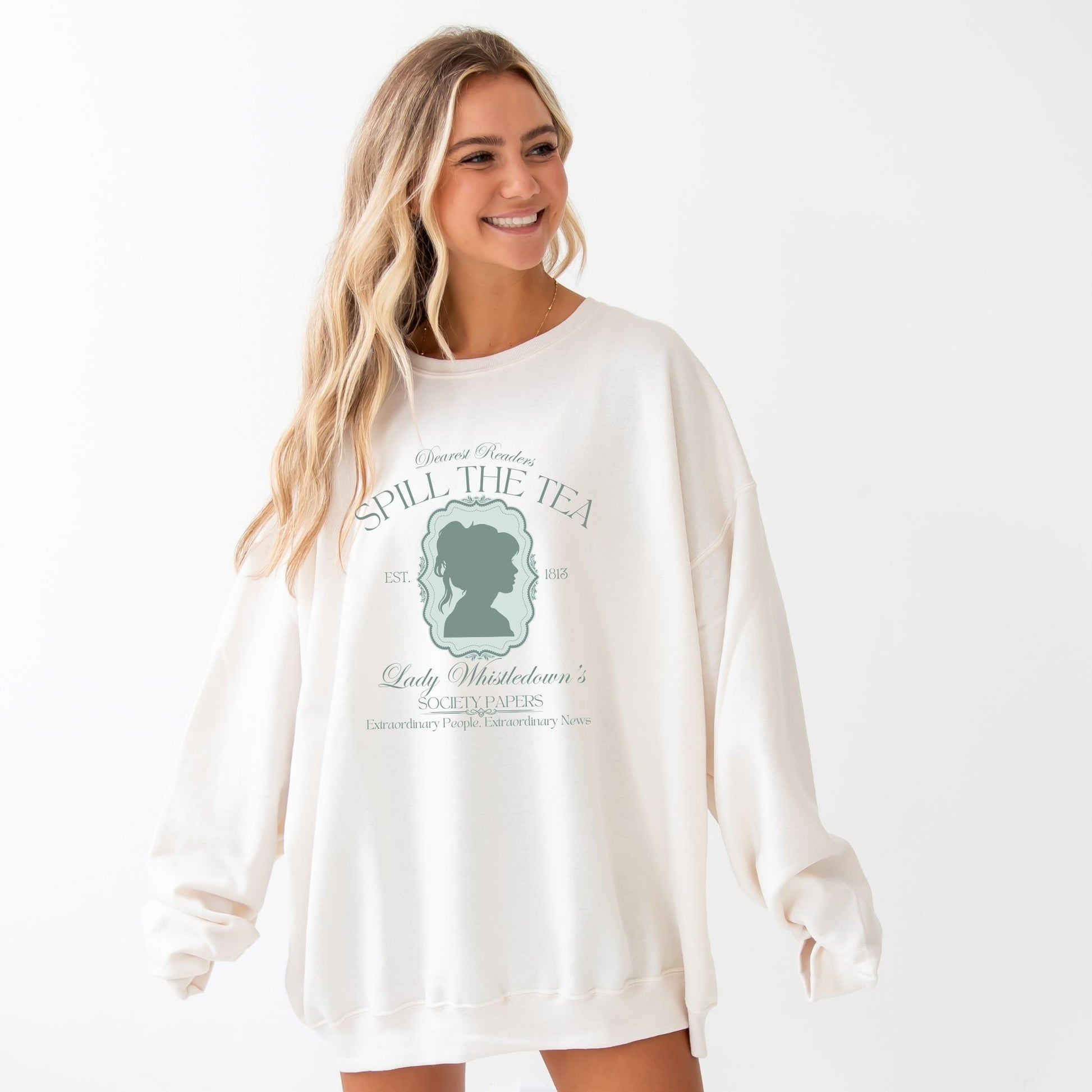 WOMAN WEARING AN OVERSIZED SWEET CREAM SWEATSHIRT WITH A SPILL THE TEA LADY WHISTLEDOWN PRINTED DESIGN